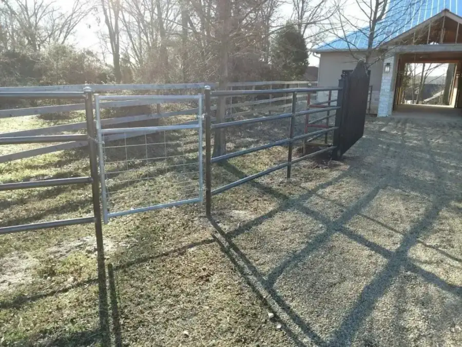 A galvanised metal panel gate and fence run beside a barn on an East Texas property
