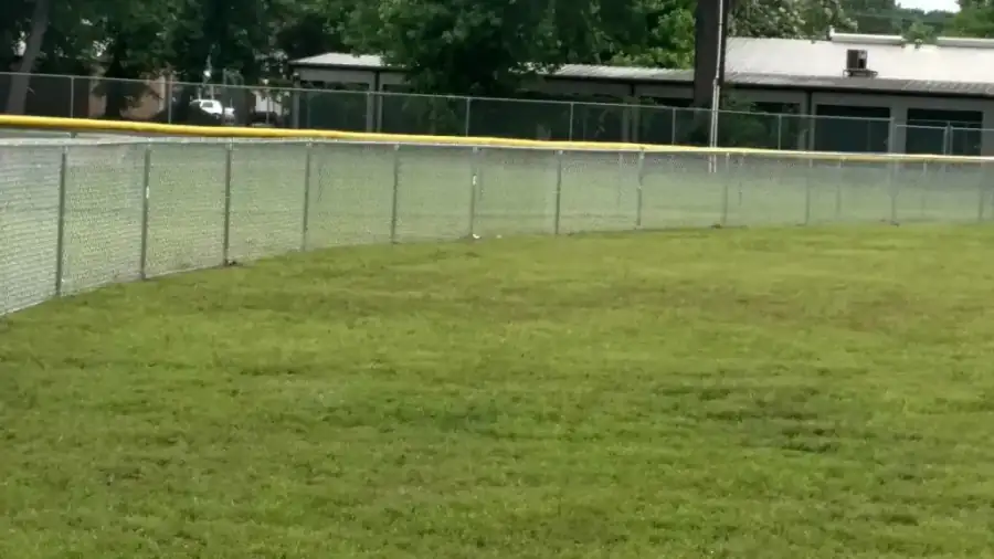 Chain link outfield fence with a yellow safety topper at a sports facility
